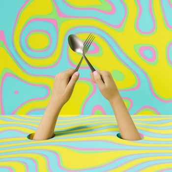 woman's hands coming out of the ground holding a spoon and fork in cross with colorful background. 3d rendering