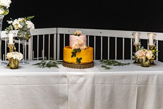 Pink and yellow wedding cake standing on table with colorful and beauty decorations around