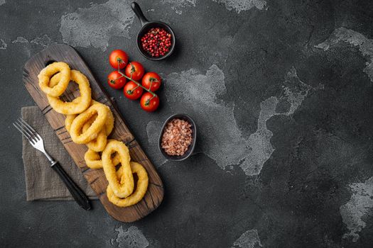 Crispy squid rings in breadcrumbs set, on black dark stone table background, top view flat lay, with copy space for text