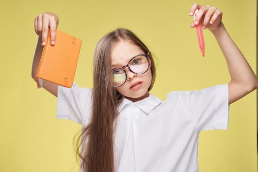 schoolgirl with textbook in hands learning childhood yellow background. High quality photo