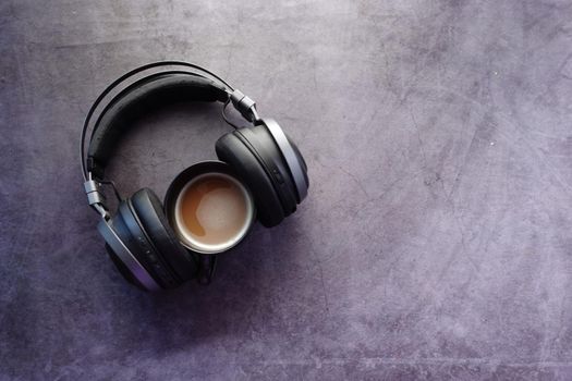 coffee and wireless headphones on black background .