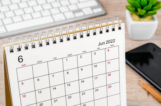 The June 2022 desk calendar on wooden table.