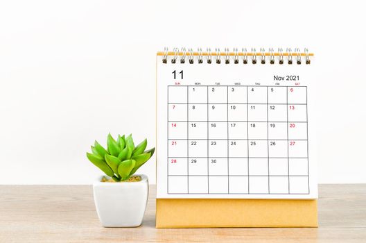 The November desk calendar 2021 with plant pot on wooden background.