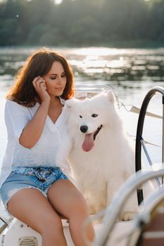 a happy woman with a big white dog on a white yacht in the sea.