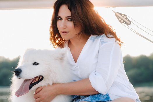 a happy woman with a big white dog on a white yacht in the sea.