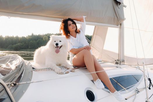 a happy woman with a big white dog on a white yacht in the sea.