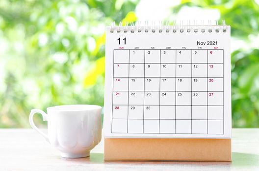 November 2021 Calendar desk for organizer to plan and reminder on wooden table on nature background.