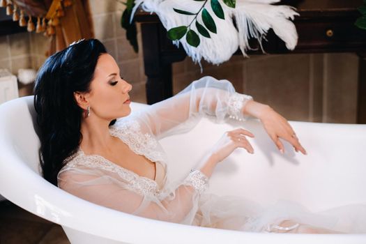 the bride, dressed in a boudoir transparent dress and underwear, lies in a vintage bathroom. Morning of the bride.
