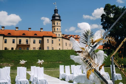 Decorated wedding arch on the background of an ancient castle.Wedding ceremony with an arch decorated with feathers in retro style.