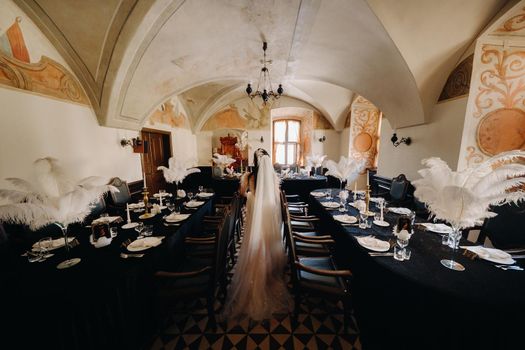 A stylish bride in a wedding dress in the interior of a restaurant decorated with feathers on the tables.