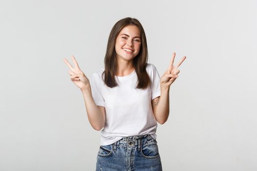 Cheerful attractive young woman smiling, showing peace gestures.