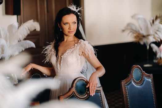 A stylish bride in a wedding dress in the interior of a restaurant decorated with feathers on the tables.
