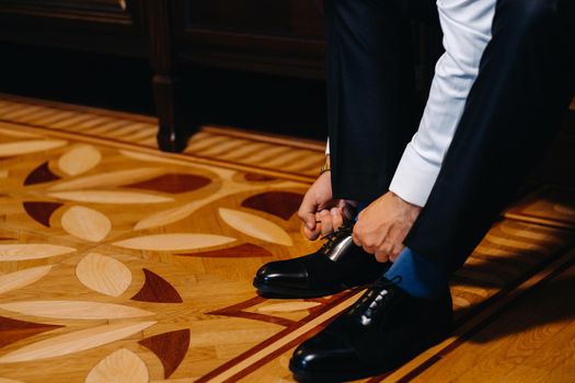 groom putting his wedding shoes. Hands of wedding groom getting ready in suit.