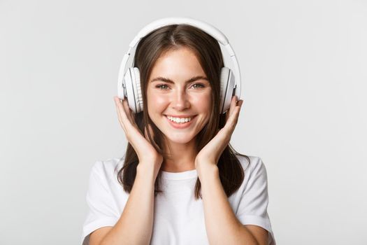 Close-up of beautiful happy girl smiling, enjoying listening music in wireless headphones.