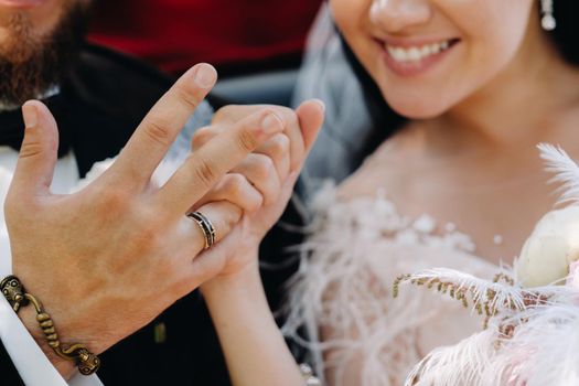 Close-up of the palms of the bride and groom with wedding rings on their hands.