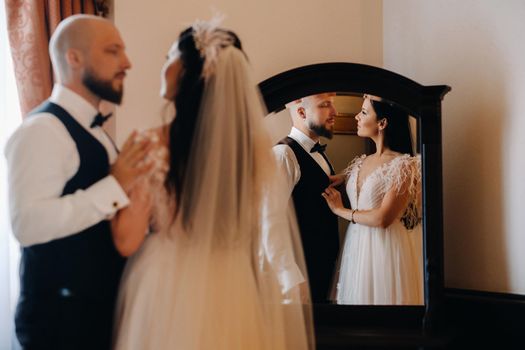 Morning of the bride. The groom stands with the bride near the mirror.