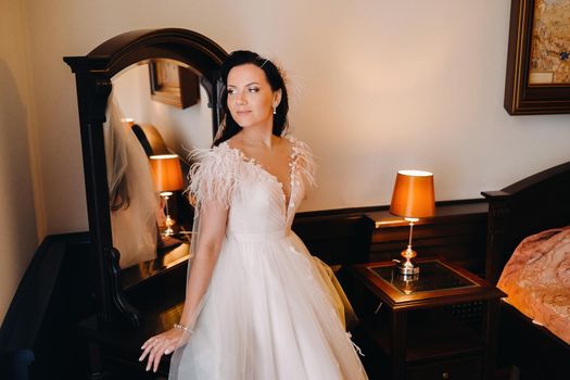 Portrait of the Bride in a wedding dress in the interior of the house near the mirror.