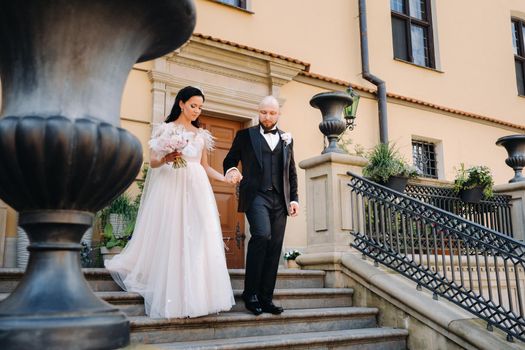 The bride and groom walk up the stairs of the Nesvizh Castle.The wedding couple descend from the stairs of the palace.
