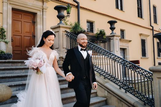 The bride and groom walk up the stairs of the Nesvizh Castle.The wedding couple descend from the stairs of the palace.