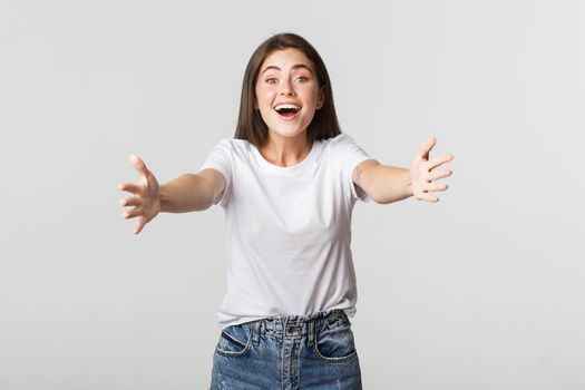 Excited beautiful girl extend hands forward, reaching for hug and smiling.