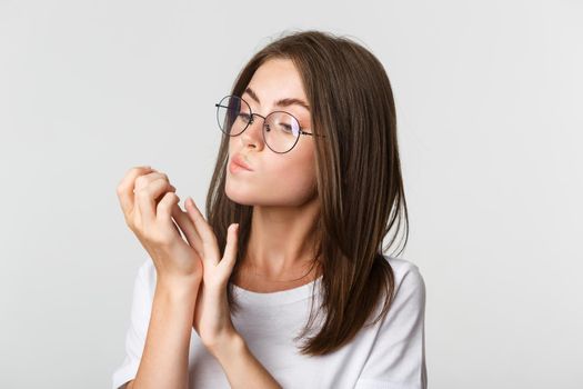 Close-up of attractive young brunette woman in glasses looking at fingernails after beauty salon.