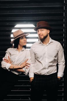 A man and a woman in white shirts and hats on a black background.A couple in love poses in the interior of the studio.