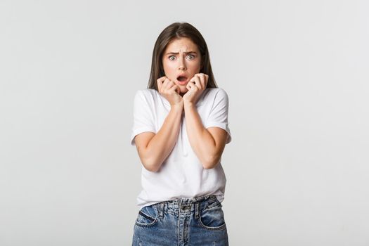 Portrait of scared and horrified young woman gasping and looking frightened.
