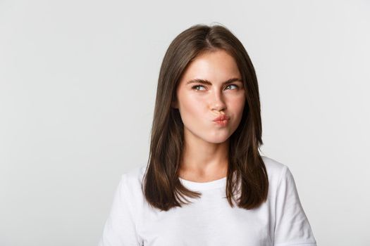 Close-up of thoughtful pretty girl looking upper left corner doubtful, thinking over white background.