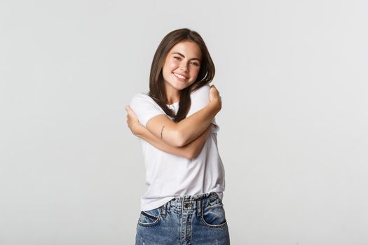 Attractive smiling tender woman hugging herself.