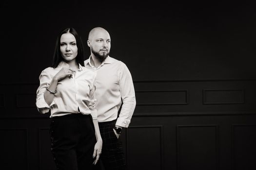 A man and a woman in white shirts on a black background.A couple in love in the studio interior.Black and white photo.