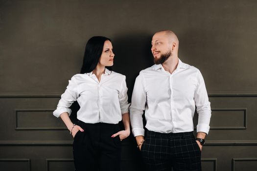 A man and a woman in white shirts on a black background.A couple in love in the studio interior.