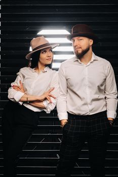 A man and a woman in white shirts and hats on a black background.A couple in love poses in the interior of the studio.