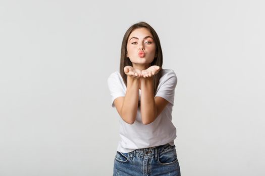Tender attractive young woman blowing air kiss at camera flirty.