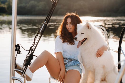 a happy woman with a big white dog on a white yacht in the sea.