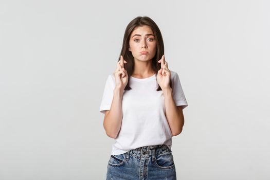 Hopeful cute brunette girl cross fingers good luck, making wish or praying.