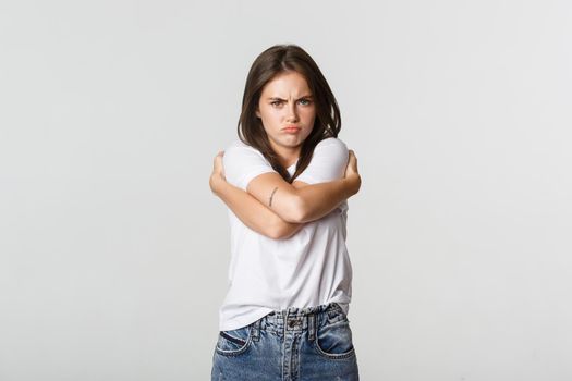 Offended sulking girl looking defensive and hugging herself.
