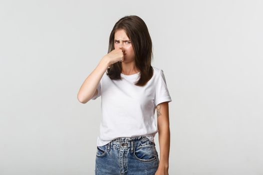 Disgusted woman shut nose and looking bothered with nasty reek, bad smell.