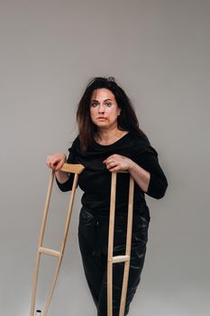 A battered woman in black clothes with casters in her hands on a gray background.