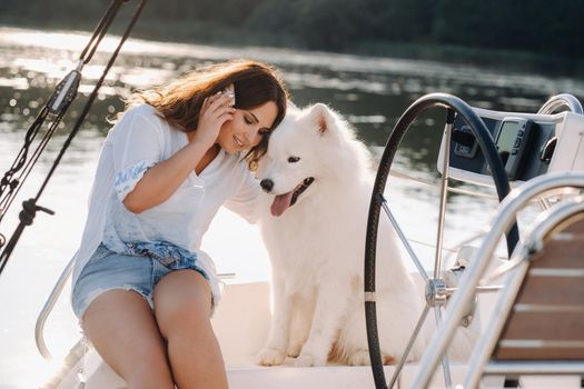 a happy woman with a big white dog on a white yacht in the sea.