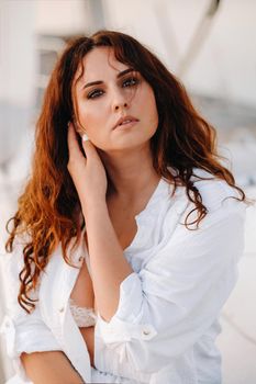 sexy woman in a white shirt enjoys the sunset on her private white yacht.