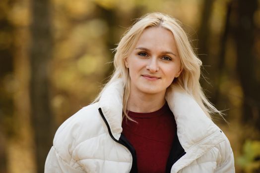 Portrait of a young blonde woman in the autumn forest.