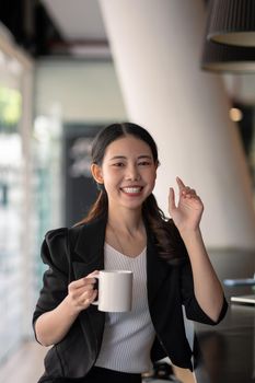 portrait smiling asian business woman pointing up and looking at the camera in modern office.