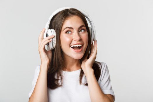 Close-up of beautiful happy girl smiling, enjoying listening music in wireless headphones.