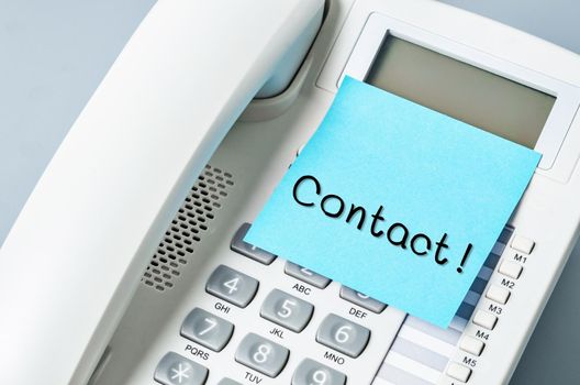 Handwritten CONTACT message on sticky note attach to IP phone.
