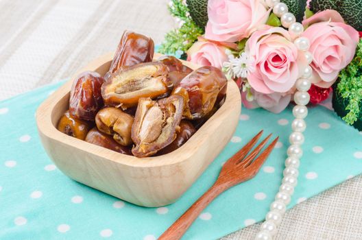 Dried dates fruit in wooden bowl and fork.