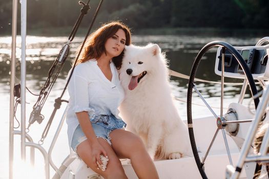 a happy woman with a big white dog on a white yacht in the sea.