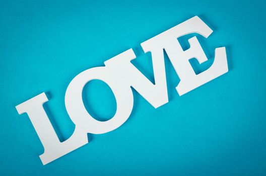 White wooden word love on blue background.