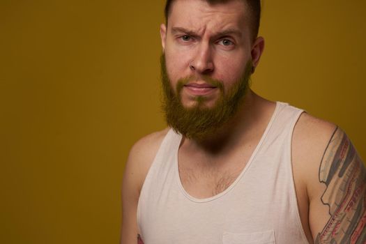 a bearded man with a serious expression in a white t-shirt with tattoos on his arms. High quality photo