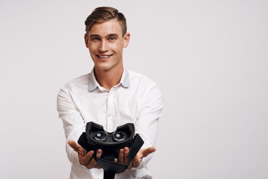 Cheerful man virtual reality glasses high-tech simulator light background. High quality photo
