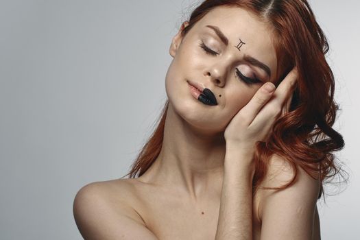 red-haired woman naked shoulders zodiac sign on face gemini. High quality photo